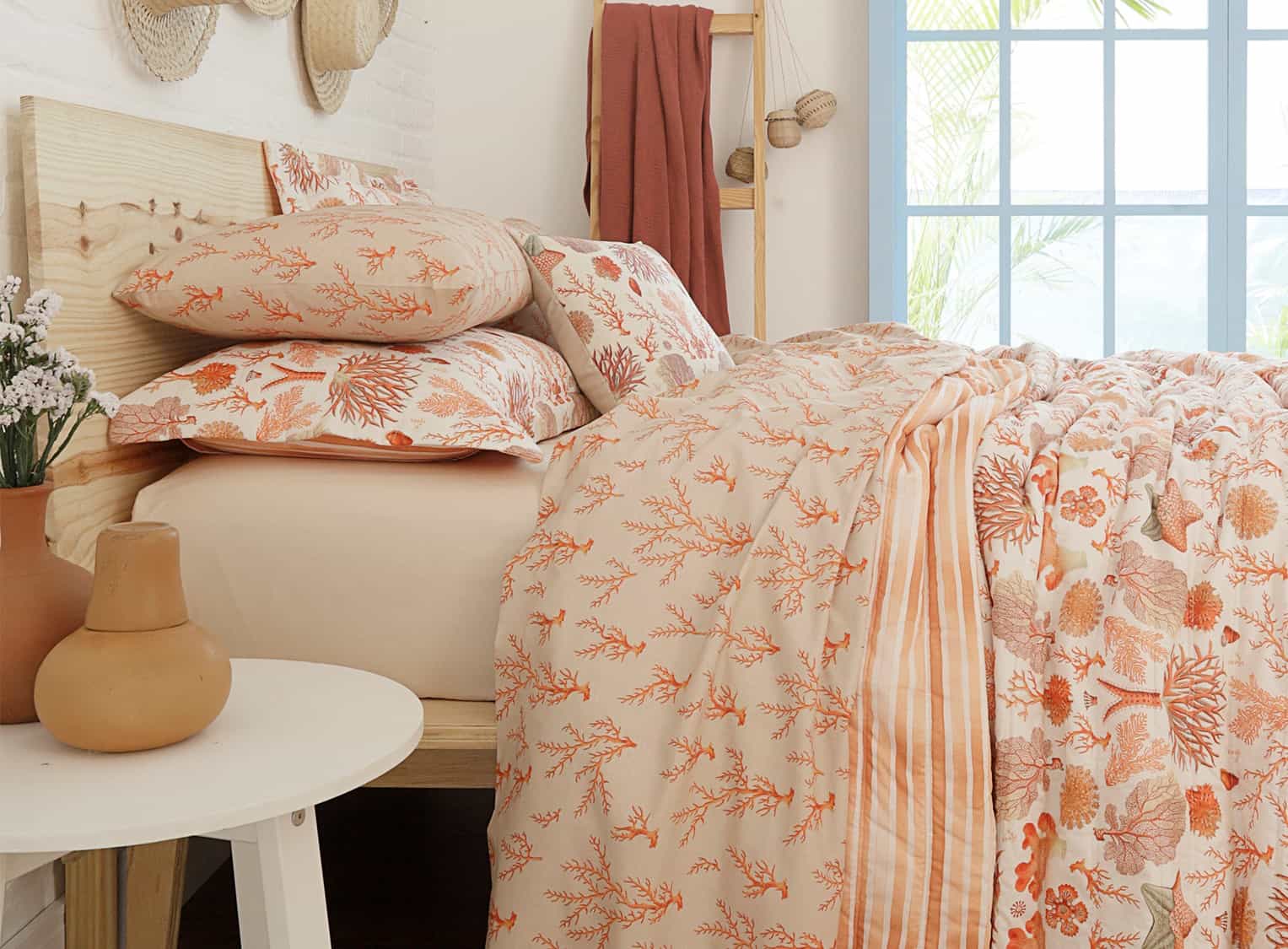 uma cama com estampa de corais alaranjada com fundo branco compõe essa cama