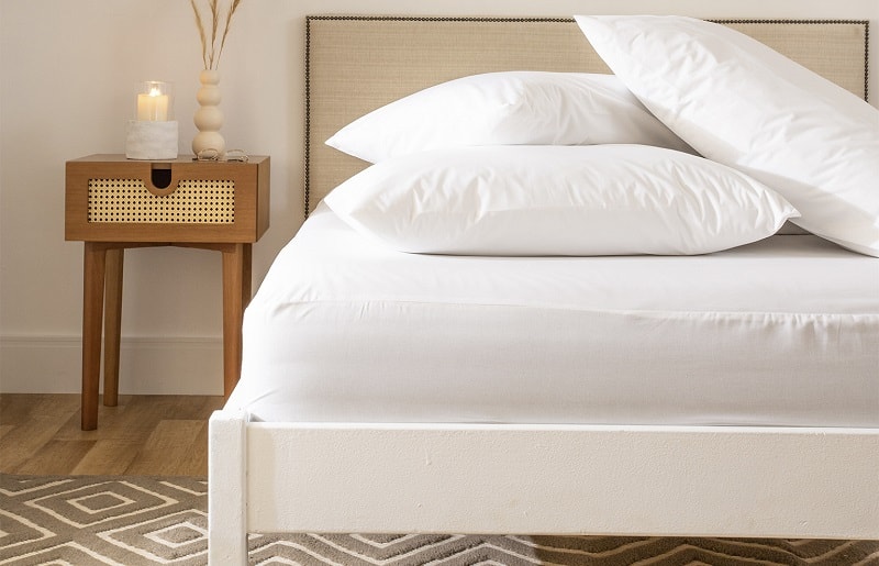 cama com travesseiros protegidos por um protetor de cama